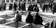 Marseille 1942: Männer sitzen auf Holzkonstuktionen, andere stehen auf einem Platz