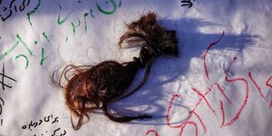 ein abgeschnittener Haarzopf auf einem wießen Blatt mit SChriftzeichen