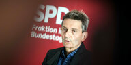 Porträt Rolf Mützenich vor einem weißen SPD-Schriftzug