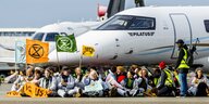 Klimaaktivisten sitzen vor einem Jet auf dem Amsterdamer Flughafen