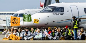 Klimaaktivisten sitzen vor einem Jet auf dem Amsterdamer Flughafen