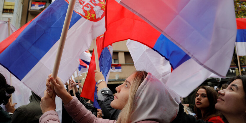 Menschen halten bei einer Protestaktion in Kosovo serbische Flaggen