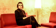 Ludmila Pogodina sitzt auf einem roten Sofa