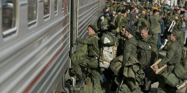 Soldaten mit Gepäck und Uniform steigen in einen Zugwaggon