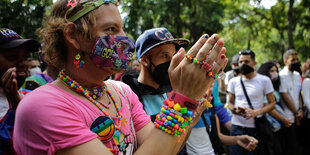 Eine bunt bekleidete Person mit lackierten Fingernägeln