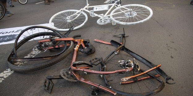 Ein zerstörtes Rennrad liegt neben einem Geisterfahrrad auf der Bundesallee, dem Unfallort