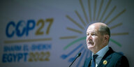 Bundeskanzler Olaf Scholz steht vor dem Logo der Weltklimakonferenz COP 27 in Ägypten