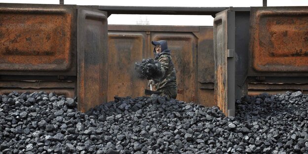 Mann schaufelt einen Berg Kohle auf