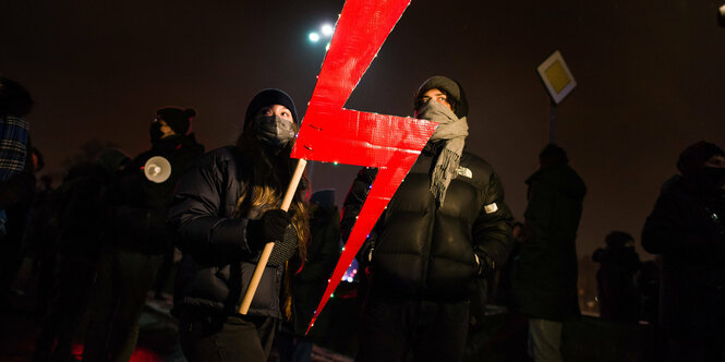 Personen mit eienm roten Blitz bei einer Demonstration.