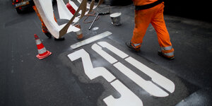 Ein Bauarbeiter markiert ein Tempo 30-Logo auf einer Straße
