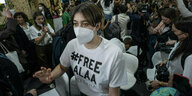 Eine Frau mit einem weißen Shirt und der Aufschrift #FreeAlaa geht durche ienn Raum mit vielen Menschen