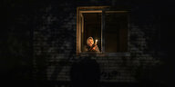 Eine Frau leuchtet in einer dunklen Wohnung mit einer Kerze