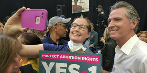 Der kalifornische Gouverneur mit einer Unterstützerin, die ein Schild in der Hand hält: Protect Arbotion Rights Yes on 1