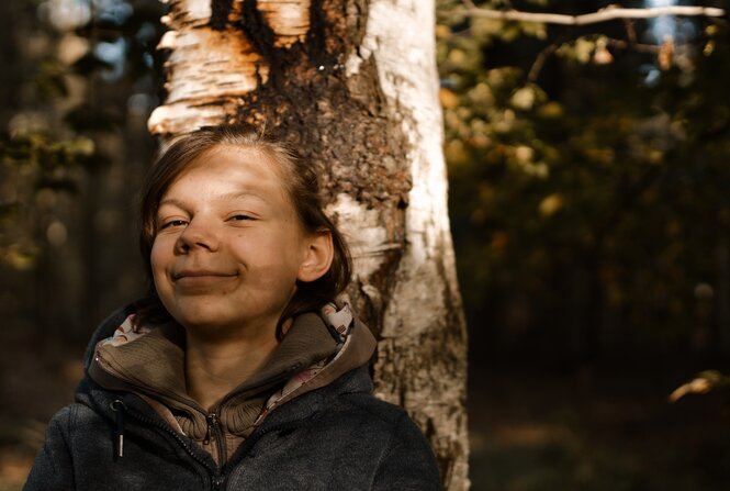 Eine Person im Sonnenlicht an einen Baum gelehnt