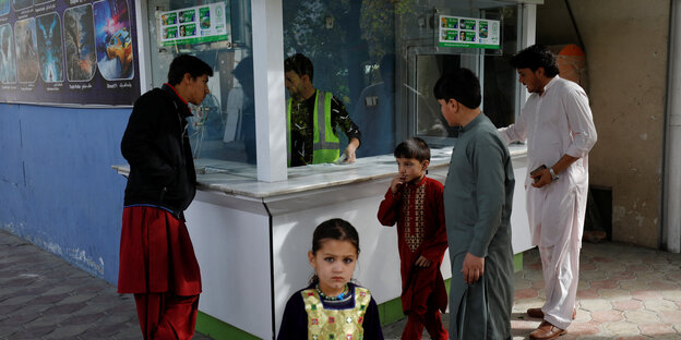 Men and a boy at a ticket booth, a little girl looks at the camera