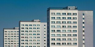 Drei Plattenbauten steht versetzt hintereindander vor blauem Himmel