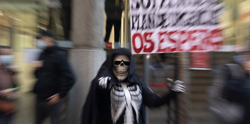 Eine als Skelett verkleidete Person bei einer Demonstration.