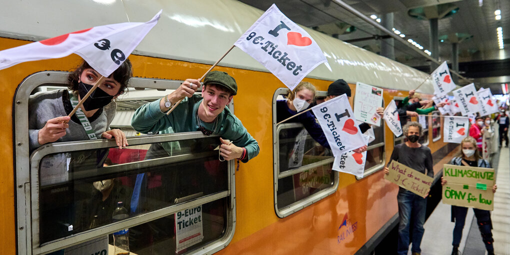 Personen mit Fahnen und Schildern an einem Zug.