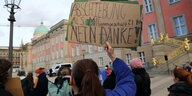 Eine Frau hält ein Plakat vor dem Brandenburger Landtag. Darauf steht: "Abschiebung als Millionengeschäft?! Nein Danke!"