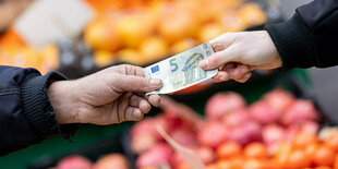 5-Euro-Schein wird auf einem Markt übergeben