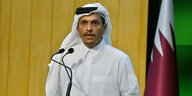 Katarische Außenminister am Rednerpult, neben ihm die Nationalflagge