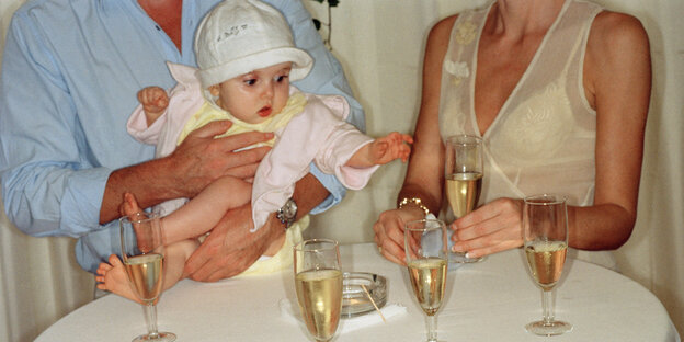People with a baby in their arms, champagne glasses in front of them.