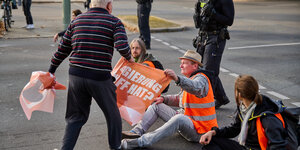 Ein Autofahrer zerrt an einem Plakat von Aktivisten.