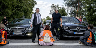 Sitzblockade von Klimaaktivist*innen auf einer Straße.