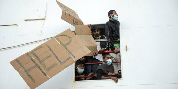 People are holding signs from a ship's hatch 