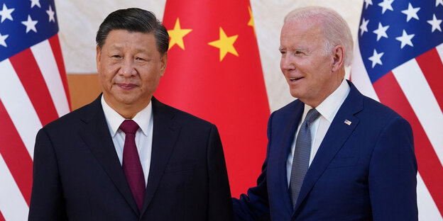 Chinas Präsident Xi Jingping schaut verdrießlich in die Kamera, während ein freundlicher Joe Biden seinen Rücken tätschelt
