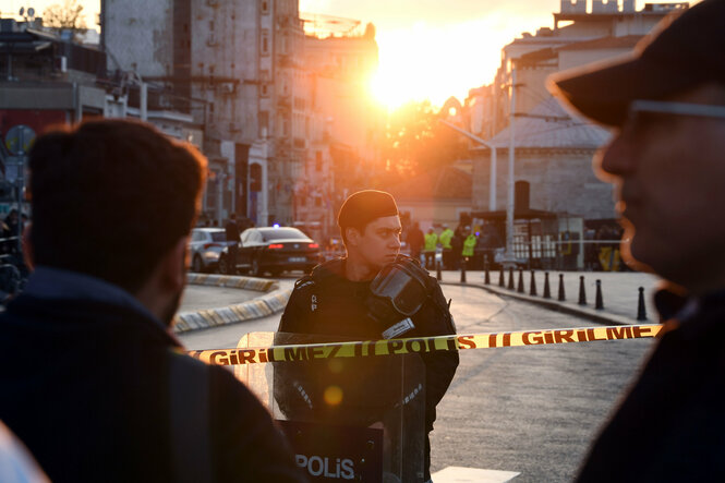 Ein Polizist vor einem Absperrband, dahinter das Istanbuler Viertel Taksim. Die Sonne wirft ein goldrötliches Abendlicht auf die Szene