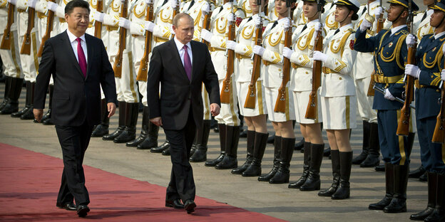 Xi Jinping and Vladimir Putin walk side by side on a red carpet at a reception