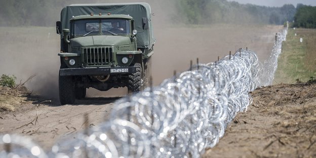 Militärlastwagen fährt den Stacheldrahtzaun an der Grenze entlang