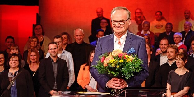 Frank Plasberg steht in den Kulissen der Sendung "Hart aber fair" und hält einen Blumenstrauss in den Händen