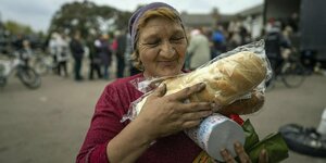 Eine Frau trägt eine Hilfslieferung mit Brot und Lebensmitteln in der Hand