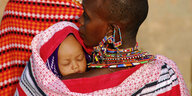 Mutter mit einem Baby . Die Masai-Frau trägt viel Perlenschmuck um ihren Hals