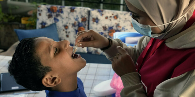 Ein Junge bekommt einen Impfstoff auf die Zunge