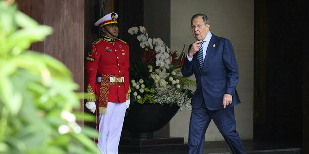 Russian Foreign Minister Lavrov walks out of a hotel in a suit