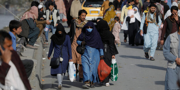 Menschen sind auf einer Straße in Kabul unterwegs, die Frauen sind verschleiert