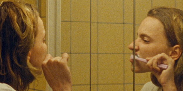 Die Schauspielerin Eva Sommer putzt sich vor einem Badezimmerspiegel die Zähne.