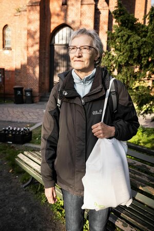 Eine Frau vor einer Kirche mit einer Tüte Lebensmittel in der Hand