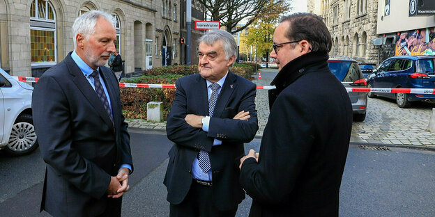 Drei Politiker - Herbert Reul, Thomas Kufen und Detlef Köbbel - stehen auf der Straße und beraten sich