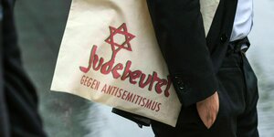 Eine Mann trägt einen Einkaufsbeutel mit Davidstern und der Aufschrift:"Judebeutel-Gegen Antisemitismus "
