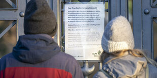 Zwei Menschen stehen vor dem geschlossenen Eingang des Zoos