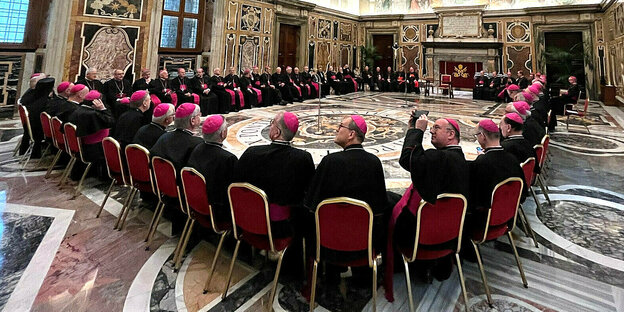 Viele Bischöfe an einem Riesentisch in einem Riesenraum im Vatikan