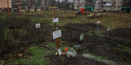 Grab auf einer Wiese mit toten Zivilist:innen