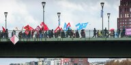 DemonstrantInnen mit mit Fahnen auf einer Brücke.