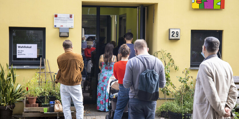 Menschen stehen vor einem Wahllokal und warten