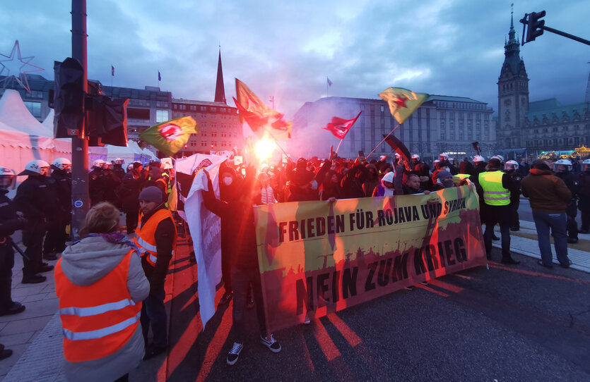 Als Reaktion auf Luftschläge des türkischen Militärs gegen kurdische Gebiete in Syrien und Irak demonstrieren Menschen in der Hamburger Innenstadt mit einem Plakat "Frieden für Rojava und Syrien. Nein zum Krieg".