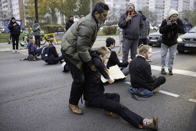 Ein Mann zerrt an einer Person in der Sitzblockade